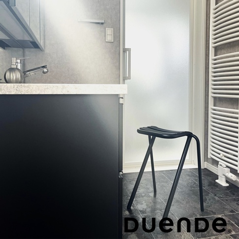 黑色金屬低吧檯椅，椅面為弧形設計，椅腳向外傾斜，置於廚房或浴室空間。