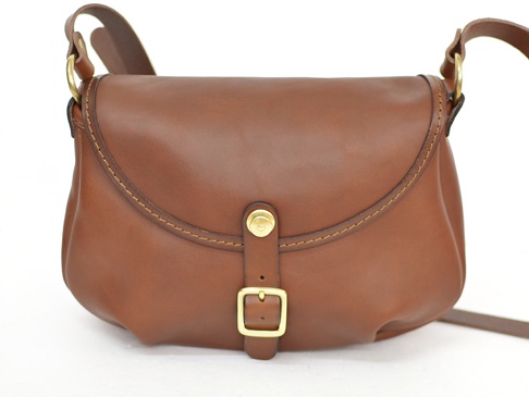 棕色皮革馬鞍包，帶有金色搭扣和可調節肩帶，適合休閒旅行。