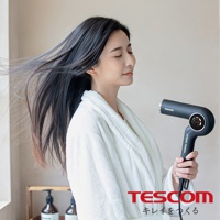 一位身穿白色浴袍的女子，正在使用TESCOM離子吹風機吹整頭髮，她的秀髮隨風飄動，臉上帶著享受的表情。