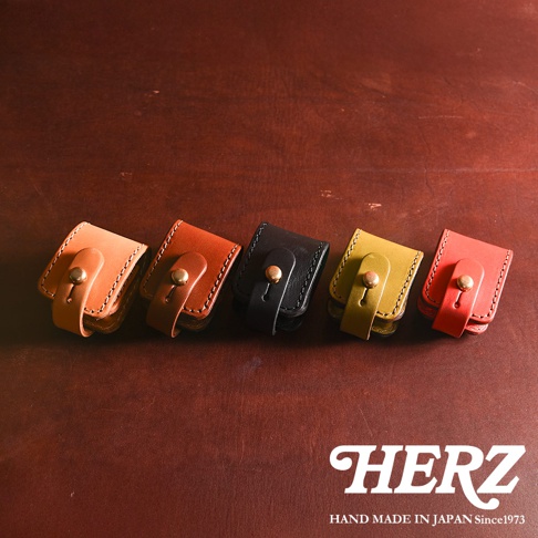 五個職人手作皮革原子釦型腰間小物收納包，顏色由左至右分別為淺棕、深棕、黑色、橄欖綠、紅色。每個收納包皆為皮革材質，有著原子釦設計，可繫於腰間。