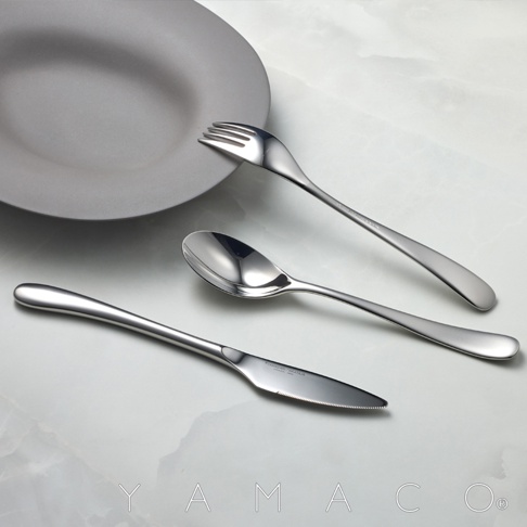 若水系列霧面不鏽鋼晚餐叉、湯匙與刀子三件組，置於灰色霧面盤旁，呈現簡約優雅的擺盤。