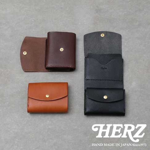 三款日本HERZ職人手作Organ系列皮革迷你短夾，分別以棕色、深咖啡色與黑色呈現，展示出皮夾開合與內部的精緻細節，右下角印有HERZ品牌字樣，展現日製手工皮革的質感。