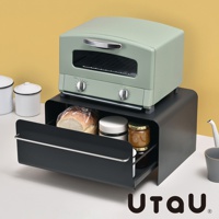 淺綠色復古烤箱置於黑色抽屜式收納櫃上方，收納櫃內有麵包、罐子和果醬。