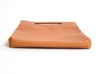 淺棕色皮革直式收納袋，頂部有提把，邊緣車縫線明顯，材質為柔軟皮革，整體呈現簡約風格。