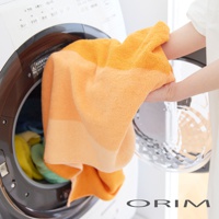 HARUKA 今治耐用絢彩拼接浴巾，橘色漸層色調，柔軟純棉材質，正在從洗衣機中取出。