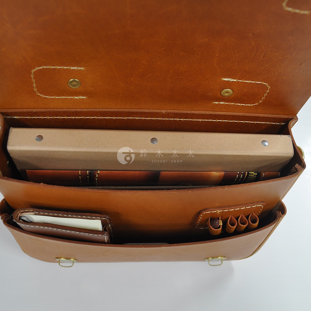 打開的棕褐色皮革公事包，內部有筆記本、文件夾和筆插，展示其精緻的縫線和簡約的設計。