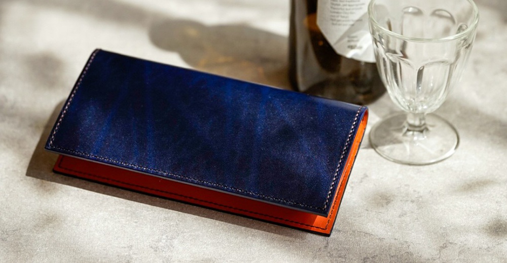 北海道KASANE職人手作比利時Rugato皮革長夾，午夜藍外層搭配橘棕色內層，具有多個卡片夾層與拉鍊零錢袋。