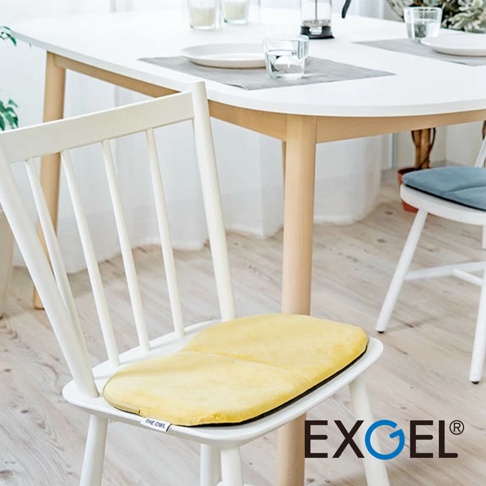 THE OWL 進階款隨身坐墊，黃色絨面材質，放置於白色木質餐椅上，坐墊邊緣為黑色。