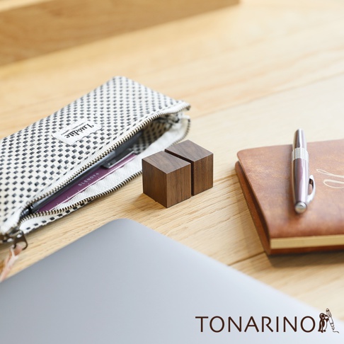 天然實木筆電散熱塊，兩個深棕色方塊狀木製支架，擺放在木質桌面，旁邊有筆記本、筆和筆袋。