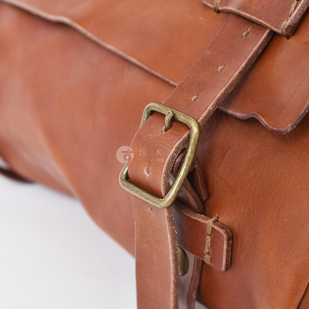 職人手作皮革復古郵差包，棕褐色皮革材質，搭配古銅色金屬扣環與皮帶，展現懷舊質感。