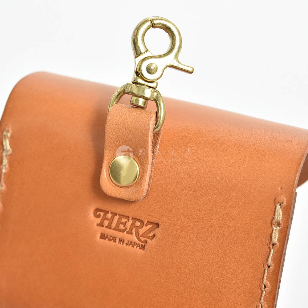 棕色皮革耳機收納包，配有金色鉤扣和品牌壓印。