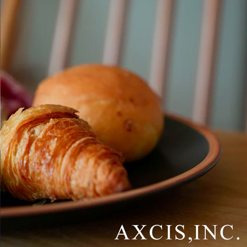 PURE 素燒百搭陶瓷主菜盤 M，深色盤中盛放著一個可頌麵包和一個圓形麵包，盤緣帶有淺棕色滾邊。