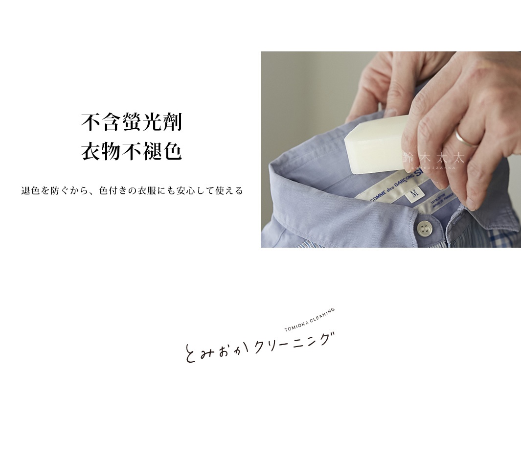 一塊白色洗衣皂，正在被一雙手塗抹在淺藍色襯衫的衣領上。