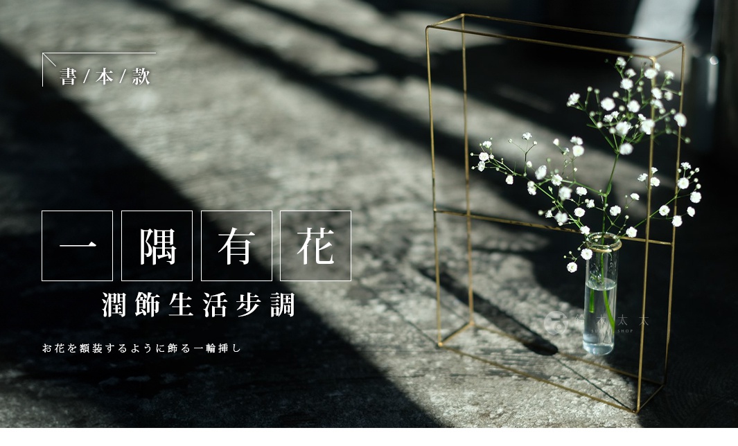 黃銅書本造型掛擺兩用花器，結構為金色金屬框架，內含一個透明玻璃試管，試管中插有白色滿天星小花。