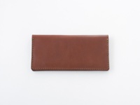 職人手作皮革簡約輕薄扁長夾，採用溫暖的棕色皮革，表面帶有細緻的紋理，邊緣以同色系線跡縫合，展現精緻工藝。