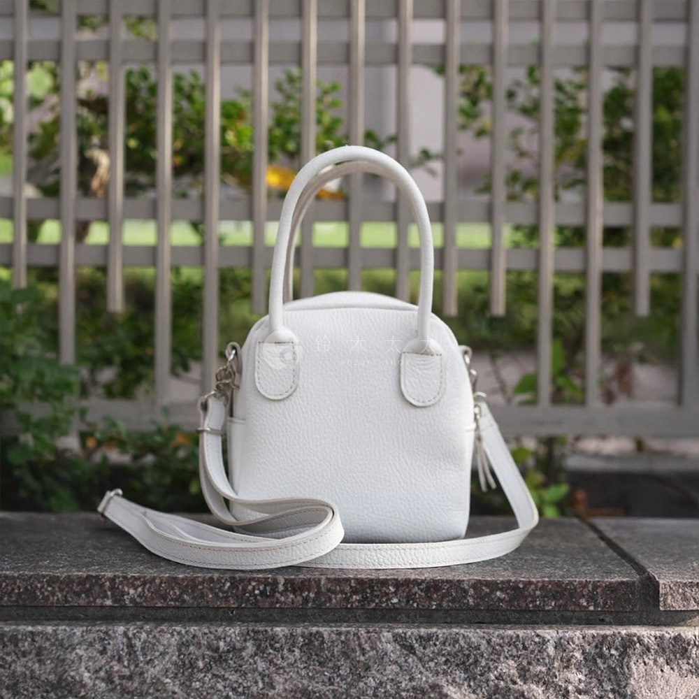 京都職人手作白色皮革貝殼包，設有手提及可拆卸肩帶，包身紋理細緻，造型簡約。