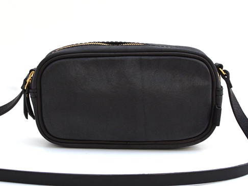 黑色皮革製成的職人手作隨身單肩小包，包身方形帶有圓潤邊緣，頂部有金色拉鍊，兩側有黑色皮革背帶。