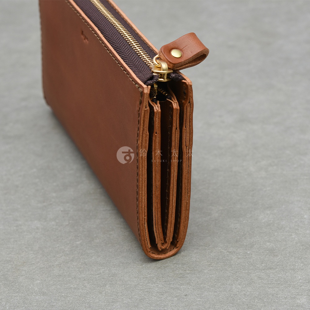 職人手作的棕色皮革長夾，拉鍊設計，側面可見多層收納空間