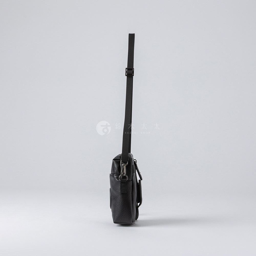 黑色皮革紋理迷你側背收納包，附有可調式黑色織帶背帶及銀色金屬拉鍊。