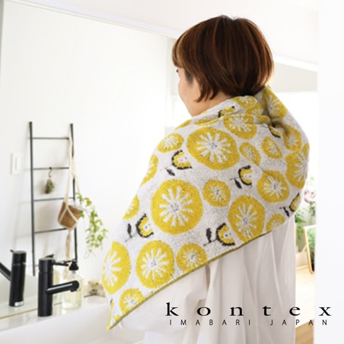 KONTEX IMABARI JAPAN 品牌字樣，一名女子裹著印有黃色花朵圖案的白色毛巾，聚焦於毛巾的特寫。