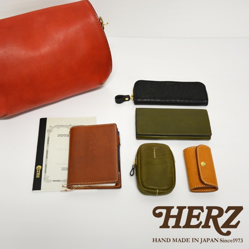 紅棕色皮革手提包、黑色拉鍊長夾、橄欖綠長夾、橄欖綠零錢包、橘色鑰匙包，以及一本筆記本。