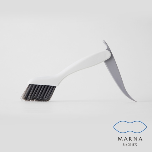 白色手柄的縫隙清潔刷，刷毛為深灰色，材質為塑膠及合成纖維。刷柄一側有淺灰色刮板設計，方便清除頑固污漬。