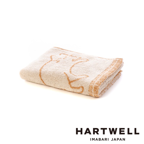 一條折疊整齊的 Hartwell 今治雙色毛巾，毛巾表面以淺米色為底，綴有棕色的貓咪線條圖案與邊框，呈現柔軟舒適的質感，右下角配有 Hartwell Imabari Japan 的黑色文字標識。