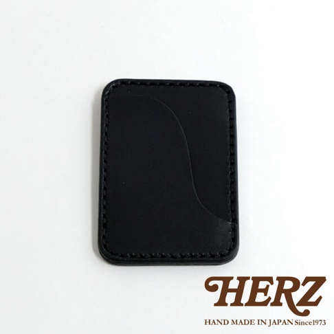 黑色皮革名片夾，有著精緻的縫線，右側有一個曲線開口，下方印有HERZ字樣和HAND MADE IN JAPAN Since1973。