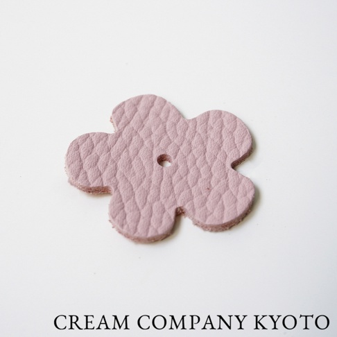 粉色皮革製成的五瓣花形吊飾，帶有細緻紋理，中央有一個小孔。