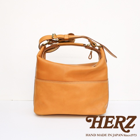 職人手作皮革單肩波士頓包，呈現自然的焦糖色調，質厚實，縫線精緻，配有可調節的皮革背帶與金屬扣環，展現簡約復古風格。