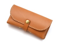 棕色皮革製成的長方形眼鏡收納盒，附有金屬釦帶和手工縫線，整體呈橫向放置於白色背景上。