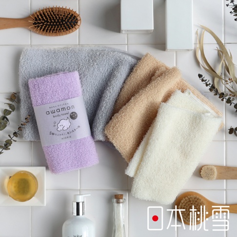 四條質地綿柔的沐浴巾，顏色為淺紫、淺灰、淺棕及米白，其中淺紫色沐浴巾上有產品標籤。