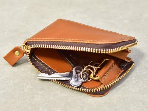 棕色皮革製作的拉鍊卡片鑰匙包，內有銀色金屬鑰匙和鑰匙圈。包包採用全包式拉鍊設計，拉鍊為深棕色，金屬部分為金色。