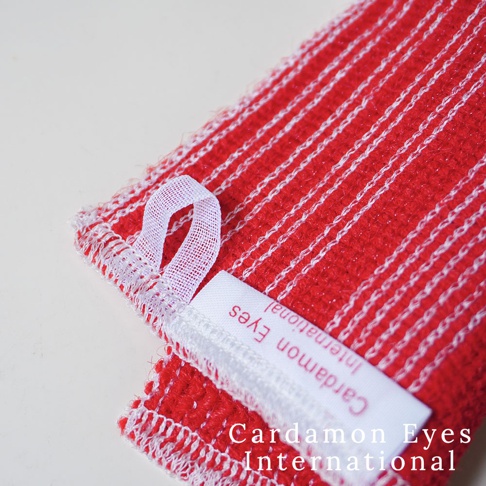 紅色壓克力纖維清潔巾，帶有白色條紋，布料材質，一角有白色網狀掛環，並附有白色標籤，上面印有「Cardamom Eyes International」字樣。