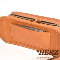 職人手作皮革騎士隨身斜背包，淺棕色皮革，設有拉鍊開口及外側手機袋，袋身車線清晰，品牌標誌壓印於手機袋上。