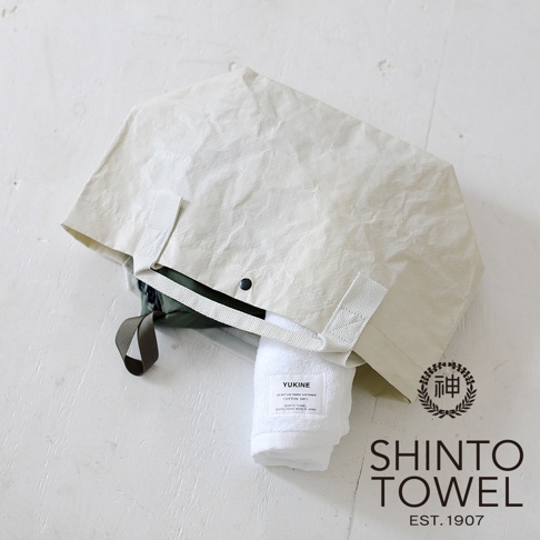 YUKINE 雪中漫步有機棉蓬厚毛巾，白色，裝在米色環保紙質購物袋中，露出部分毛巾上有品牌標籤。