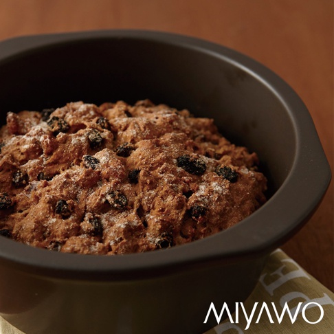 深灰色陶土湯鍋，內盛裝著有葡萄乾的烘焙食品，表面撒有細砂糖。