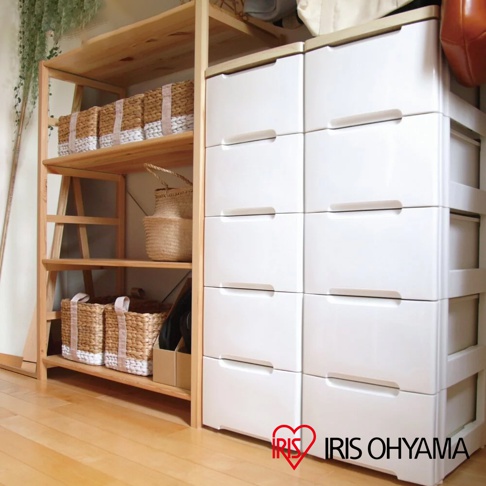 白色四層抽屜收納櫃，附有淺色木紋邊緣和嵌合式把手，旁邊是木製層架，上面擺放著草編收納籃。