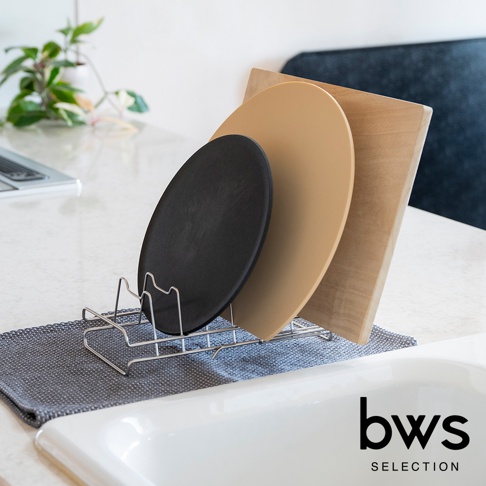 bws SELECTION 不鏽鋼可伸縮簡約瀝水架展示了三種不同顏色的圓形和方形砧板，整齊地擺放在廚房水槽旁的灰色布墊上。