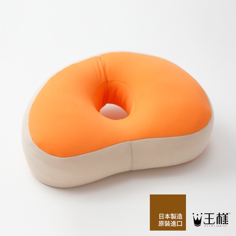 王樣午睡枕，橘色與米色拼接設計，柔軟布面材質，中央有圓形孔洞，適合午間休息。