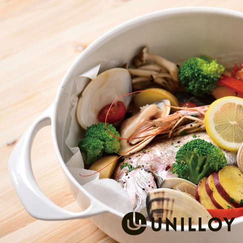 白色琺瑯鑄鐵鍋裝有海鮮、蔬菜和檸檬，鍋內鋪有烘焙紙，置於木質桌面。