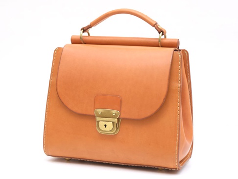 淺棕色皮革製成的手提包，帶有翻蓋和金色金屬鎖扣，頂部有提把。