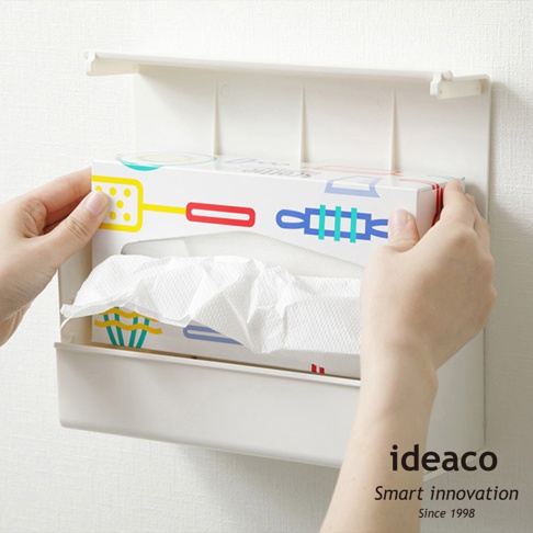 白色ABS材質的壁掛/桌上兩用擦手紙架，架上裝有印有彩色圖案的擦手紙盒，盒內露出白色擦手紙。
