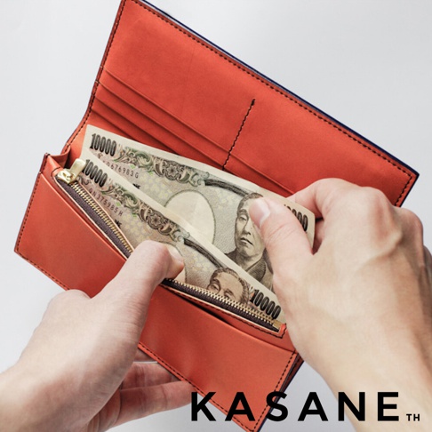 KASANE 品牌橘棕色內襯長夾，展示放入的日圓千元鈔票，鈔票上印有數字10000字樣，強調其日本製造的特點。