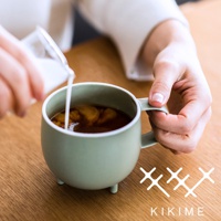 一個淺綠色的美濃燒珪晶釉球型馬克杯，帶有三個支腳，杯中盛有咖啡，正有人倒入牛奶。