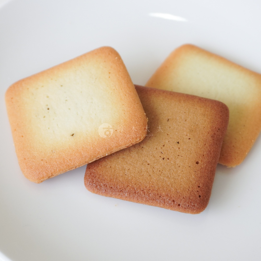 三塊方形的蘇打餅乾，兩塊堆疊在一起，一塊則放在上面，呈現淺黃色和較深的褐色。
