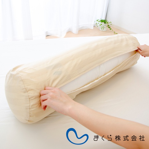 圓柱形夾腿枕，米白色條紋枕套，枕套拉開露出白色枕芯，兩隻手正在調整枕套。