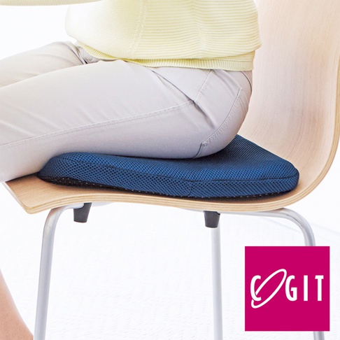 深藍色蜂巢式凝膠坐墊，附有網狀布套，放置於木質椅子上，由一位穿著淺黃色毛衣和米色褲子的人坐著。