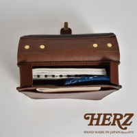 職人手作皮革三口袋三用後背包，棕色皮革，內部放有筆記本與藍色印花布，頂部有金屬扣環。