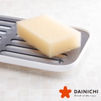 淺黃色海綿靜置於白色塑膠與灰色金屬材質的瀝水架上，海綿表面紋理細密。